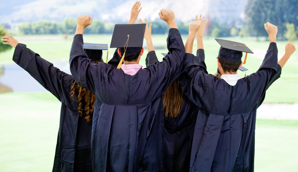 Excited group of people on their graduation day with arms up